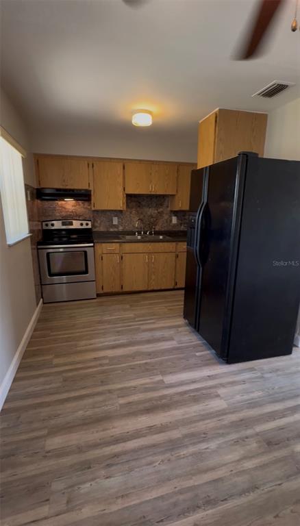 A kitchen features light wood cabinets, a stainless steel stove, and a black refrigerator — 2240 WHITE SANDS DRIVE, TITUSVILLE, FL