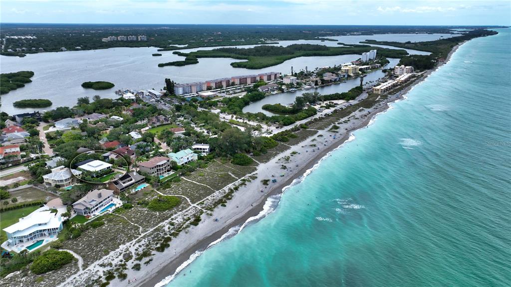 An aerial view shows a coastal neighborhood with houses along a sandy beach and water — 1145 HORIZON VIEW DRIVE, SARASOTA, FL