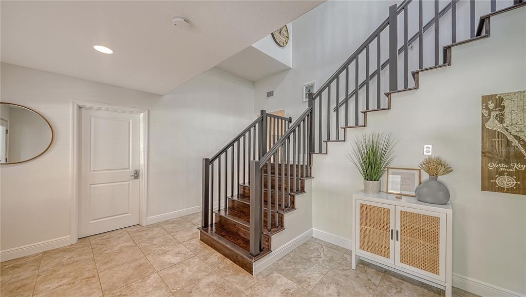 An entryway features a tiled floor, a staircase with dark railings, and a small cabinet — 1145 HORIZON VIEW DRIVE, SARASOTA, FL