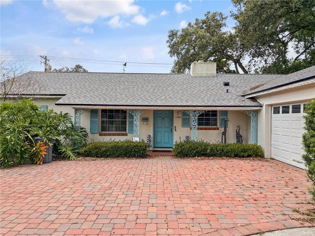 A single-story house with a brick driveway, light blue door, and decorative metal porch supports — 2340 DERBYSHIRE ROAD, MAITLAND, FL