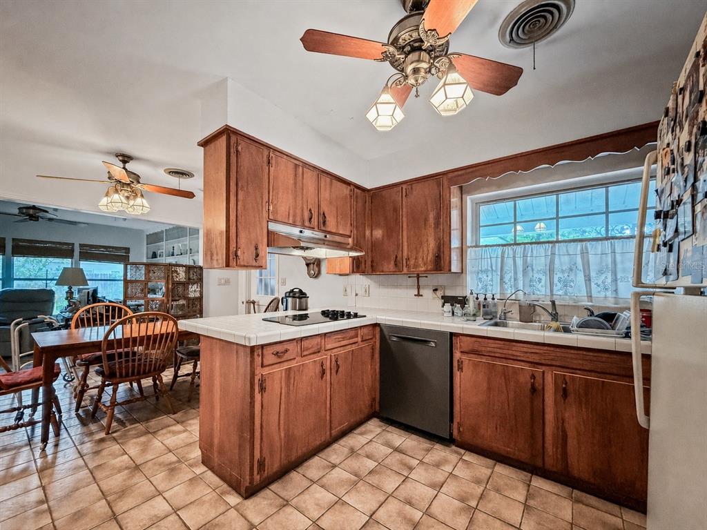 A kitchen with wood cabinets, tiled countertops, and a dining area with a ceiling fan — 2340 DERBYSHIRE ROAD, MAITLAND, FL
