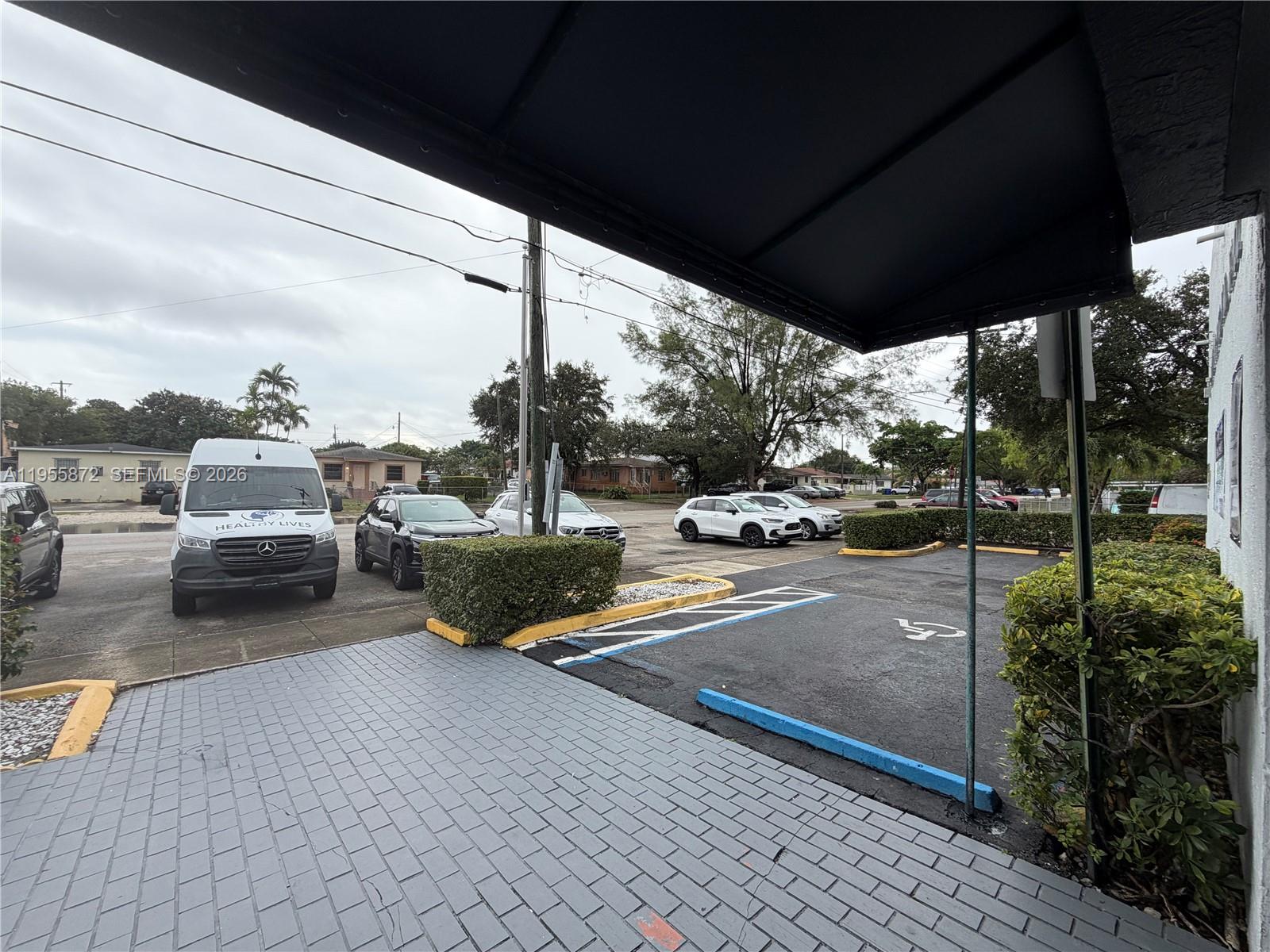 An outdoor view shows a paved parking lot with a handicap space and several vehicles — 600 NW 35th Ave # 201, Miami FL 33125, MIAMI, FL