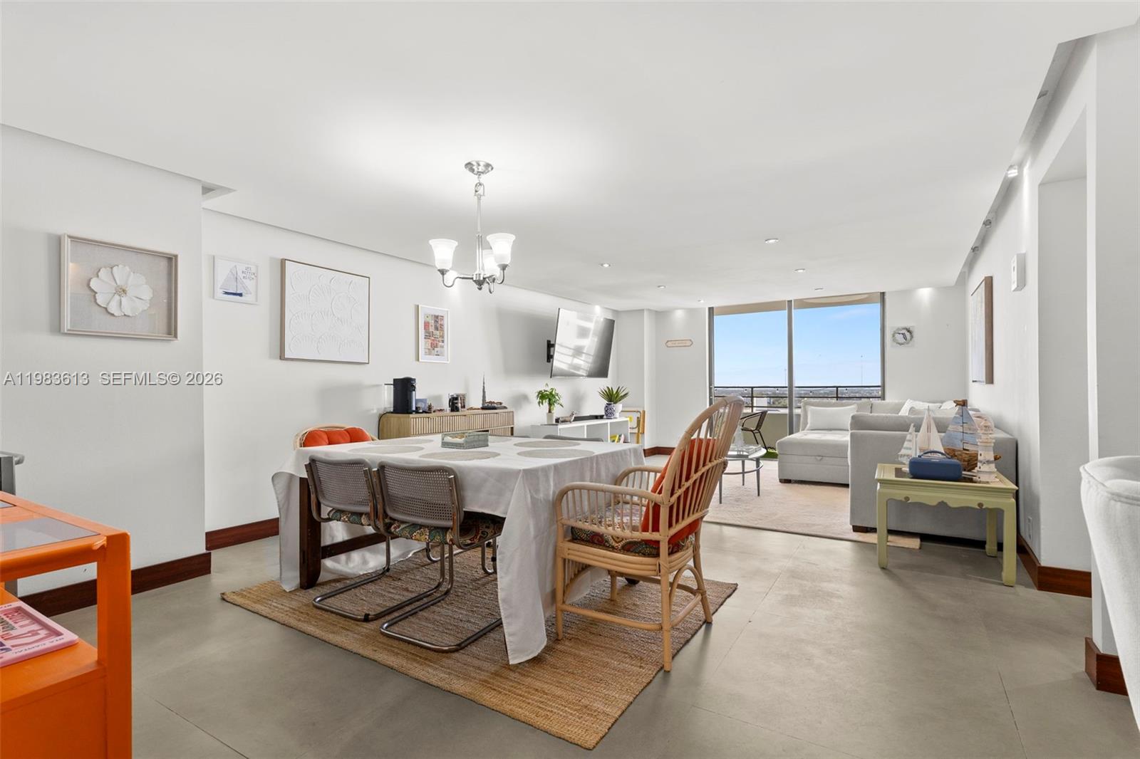 A dining area with a table and chairs leads into a living room with balcony access — 2500 Parkview Dr # 2319, Hallandale Beach FL 33009, HALLANDALE BEACH, FL
