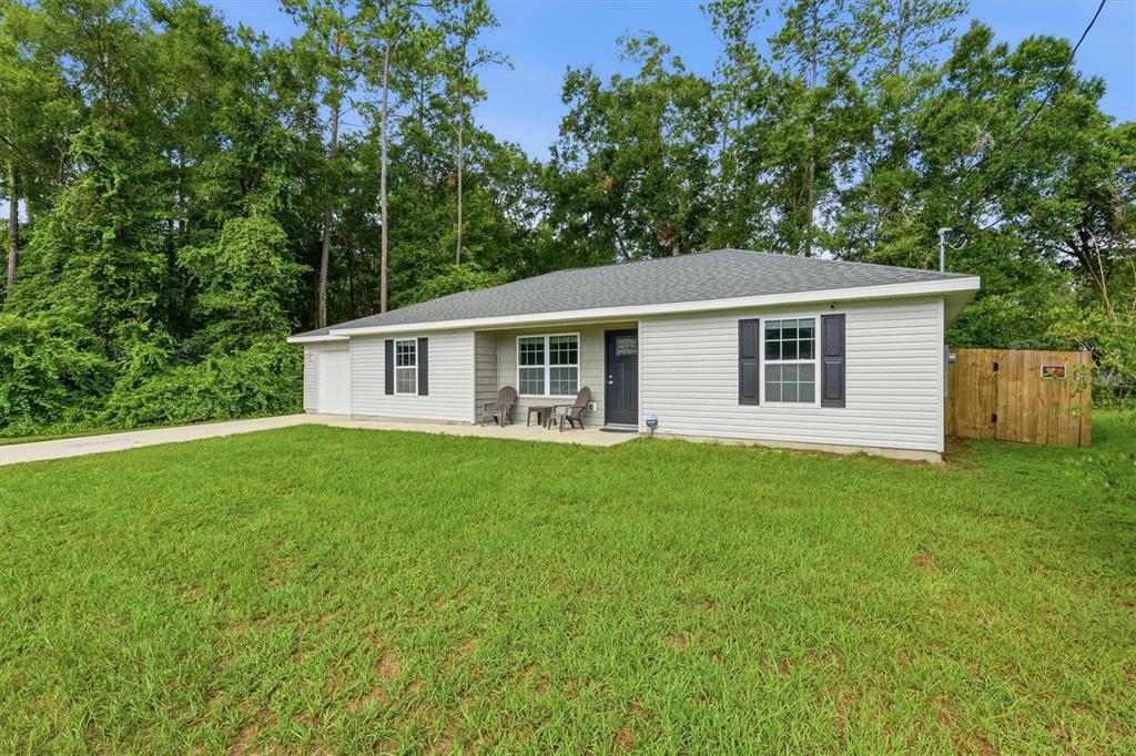 A single-story house with light gray siding, a dark front door, and a grassy yard — 4918 NW 61ST COURT, OCALA, FL