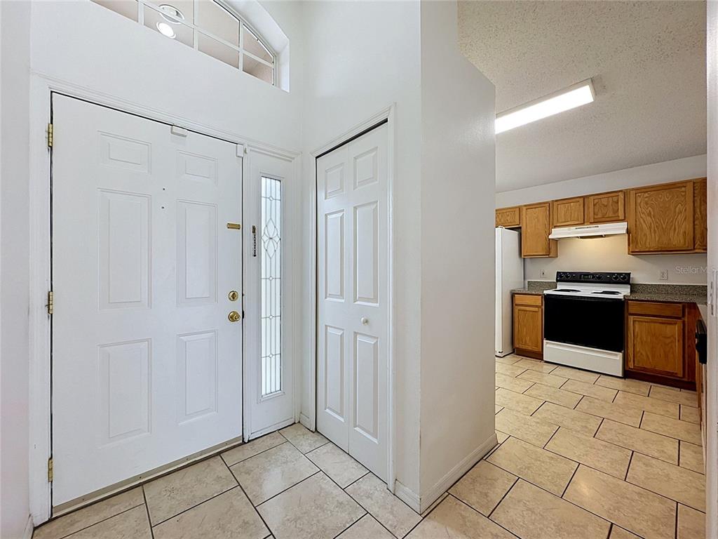 An entryway with tile flooring leads to a kitchen featuring wood cabinets and white appliances — 659 DURANGO LOOP STREET, DAVENPORT, FL