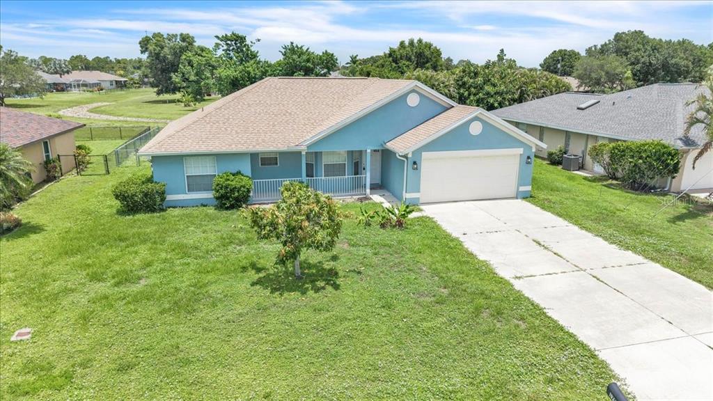 A light blue single-story house with a white garage door and a concrete driveway — 1708 BLUE LAKE CIRCLE, PUNTA GORDA, FL
