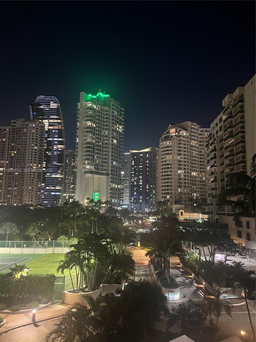 An elevated night view of a city skyline featuring several high-rise residential buildings and palm trees — 520 Brickell Key Dr # A610, Miami FL 33131, MIAMI, FL