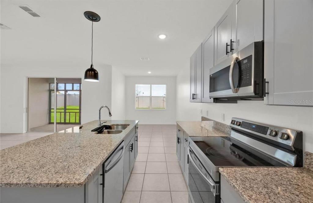 A kitchen with gray cabinets, granite countertops, stainless steel appliances, and a large island — 811 RICHMOND ESTATE AVENUE, HAINES CITY, FL