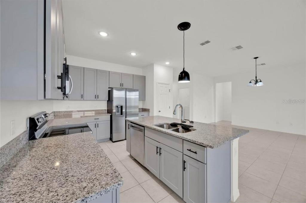 A kitchen with gray cabinets, granite countertops, a center island, and stainless steel appliances — 811 RICHMOND ESTATE AVENUE, HAINES CITY, FL