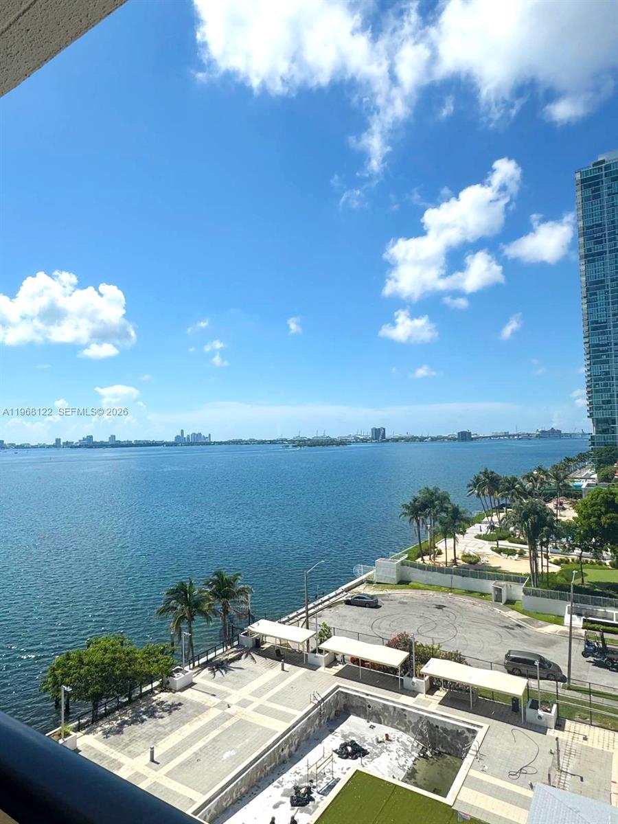A balcony with a glass railing overlooks a bay and a paved courtyard below — 600 NE 36th St # 820, Miami FL 33137, MIAMI, FL