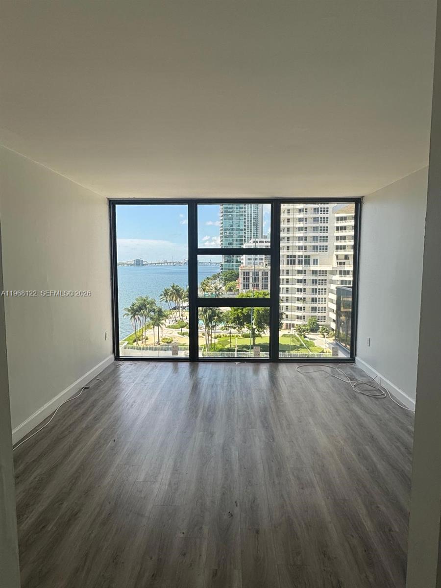 A room with floor-to-ceiling windows overlooking a bay, a park, and city skyscrapers — 600 NE 36th St # 820, Miami FL 33137, MIAMI, FL
