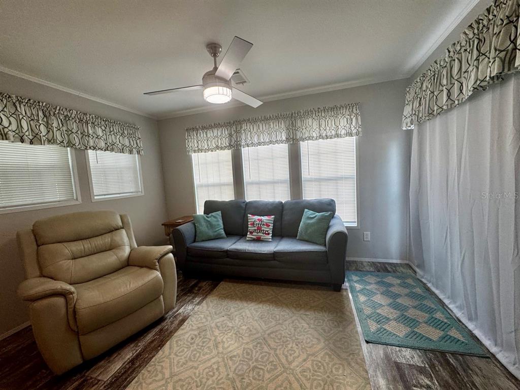 A living room features a beige recliner, a grey sofa, and wood-look flooring — 14365 NE 252ND COURT ROAD UNIT 123, SALT SPRINGS, FL