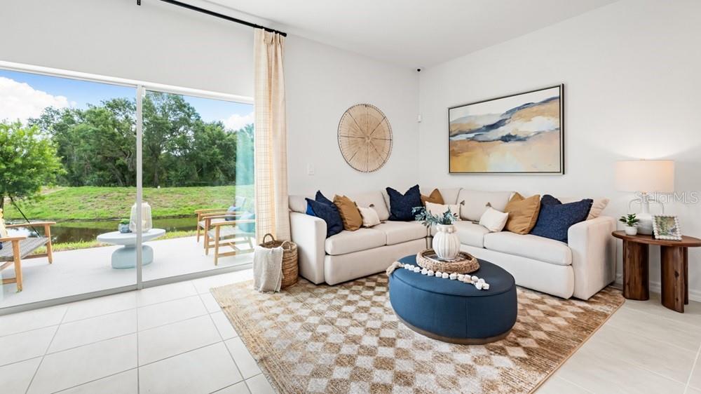 A living room features a beige sectional sofa, a blue ottoman, and a sliding glass door — 10830 ECLIPSE STREET, SARASOTA, FL