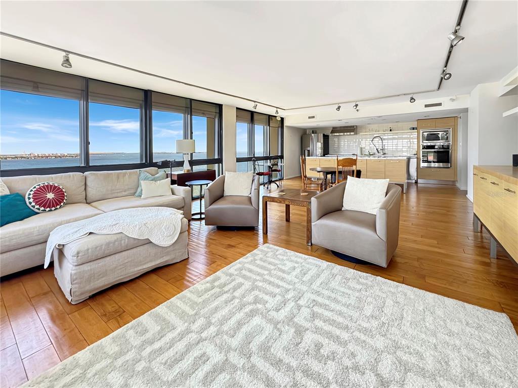 An open-concept living room features hardwood floors, a large area rug, and floor-to-ceiling windows — 3301 BAYSHORE BOULEVARD UNIT 2003D, TAMPA, FL