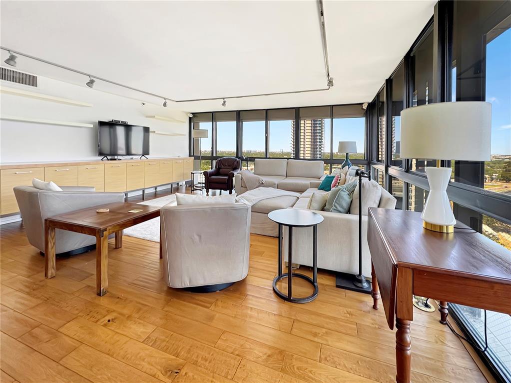 A bright living room features hardwood floors, floor-to-ceiling windows, and a large sectional sofa — 3301 BAYSHORE BOULEVARD UNIT 2003D, TAMPA, FL