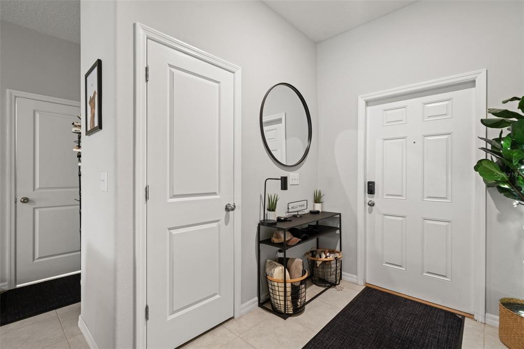 An entryway features a white front door, a console table with storage baskets, and a mirror — 7627 FRENCH MARIGOLD AVENUE, TAMPA, FL
