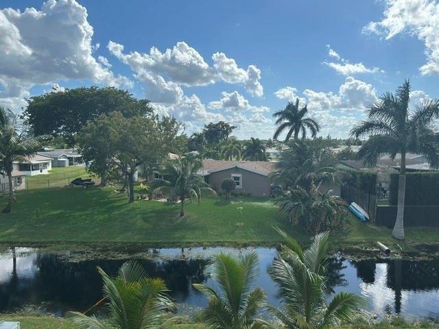 A view of a canal, green lawn, palm trees, and houses under a cloudy sky — 6770 Royal Palm Boulevard # 301, Margate FL 33063, MARGATE, FL