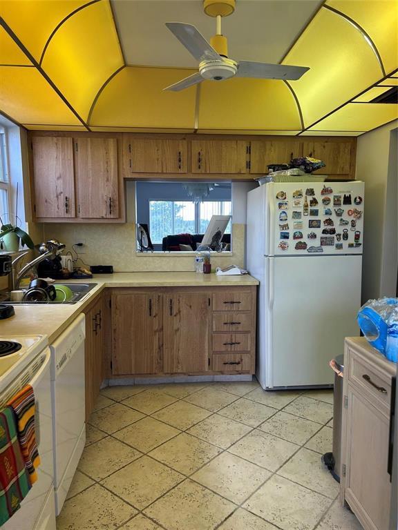 A kitchen features wood cabinets, a white refrigerator, and a yellow soffit with a fan — 6770 Royal Palm Boulevard # 301, Margate FL 33063, MARGATE, FL