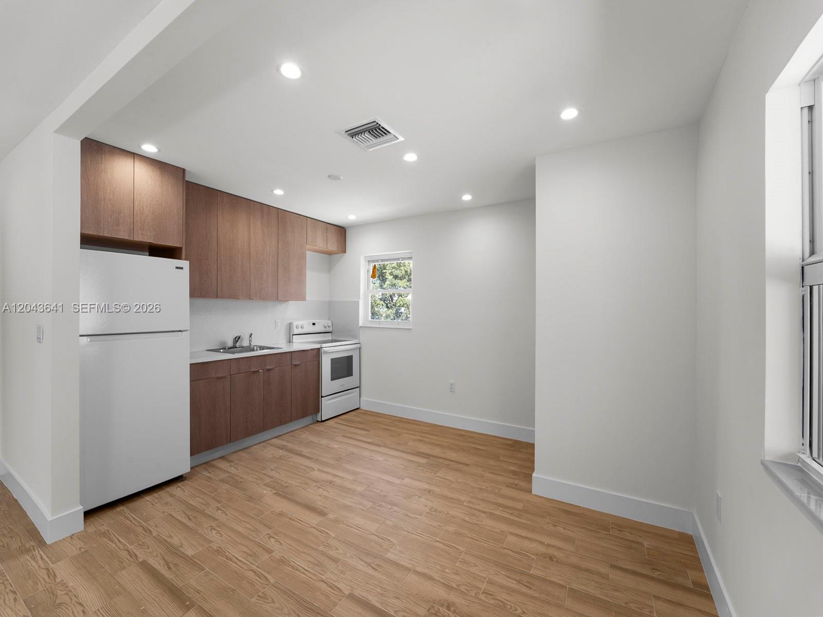 A kitchen features wood-toned cabinets, white appliances, and light wood-look flooring — 238 NW 41st Ave # 0, Miami FL 33126, MIAMI, FL