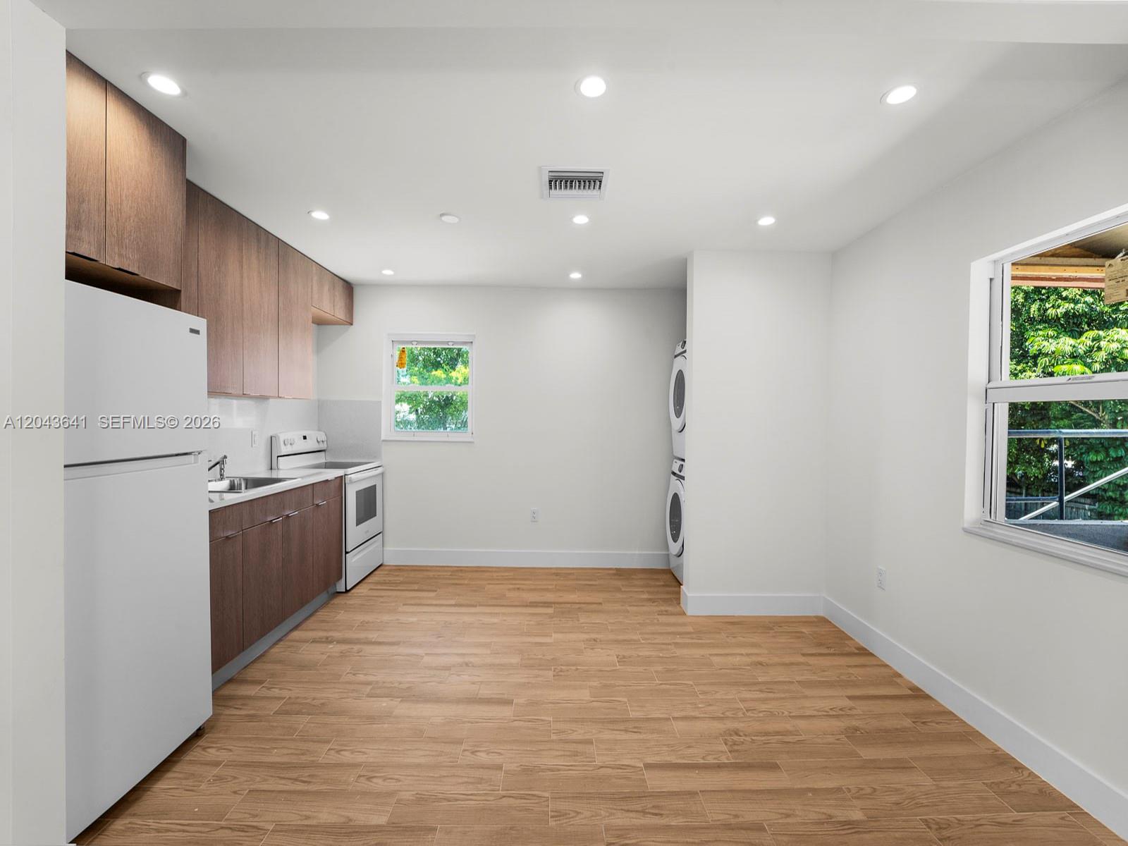 A kitchen with wood cabinets, white appliances, and a stacked washer-dryer unit — 238 NW 41st Ave # 0, Miami FL 33126, MIAMI, FL