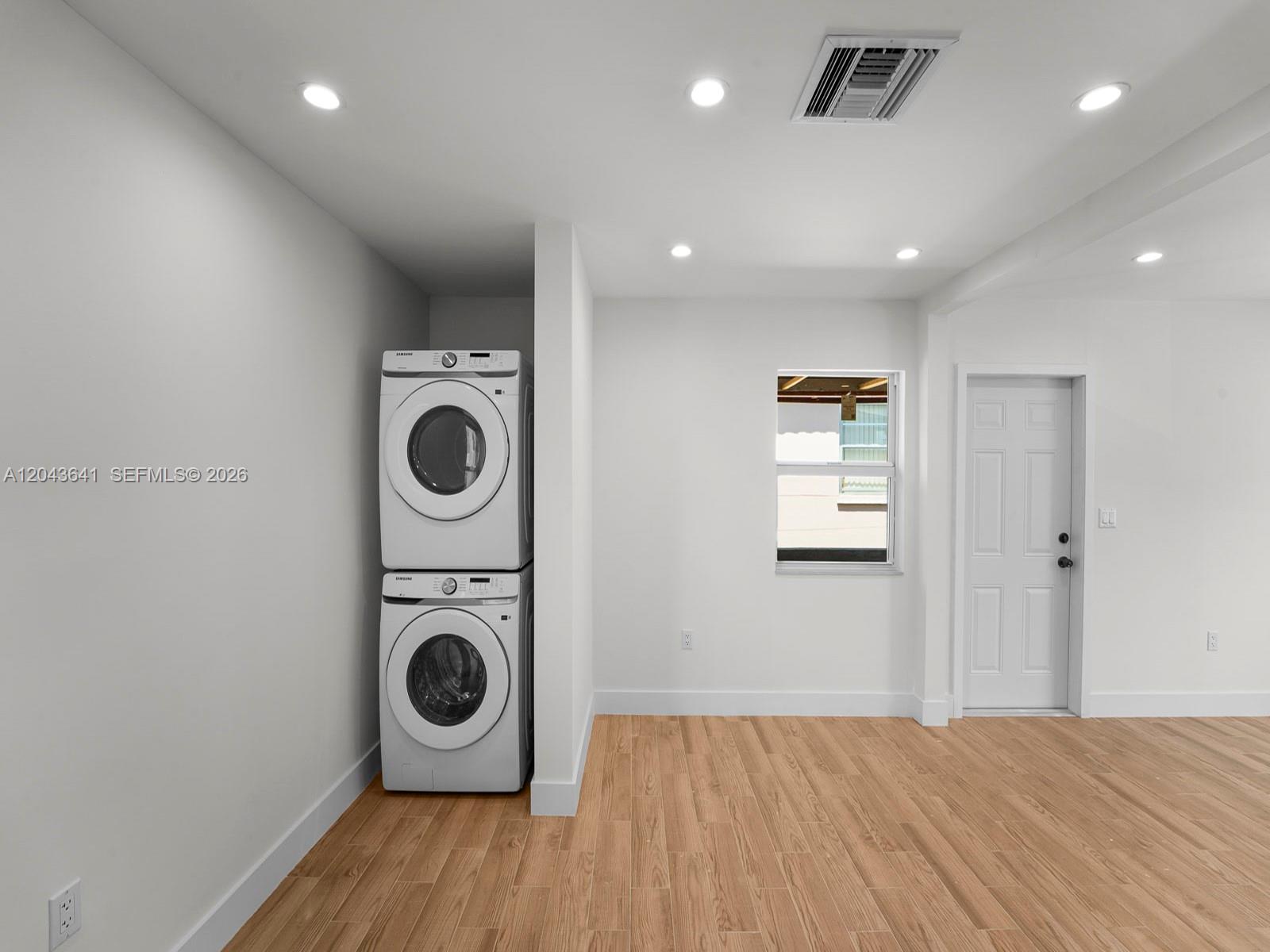 A laundry area features a stacked washer and dryer set on wood-look tile flooring — 238 NW 41st Ave # 0, Miami FL 33126, MIAMI, FL