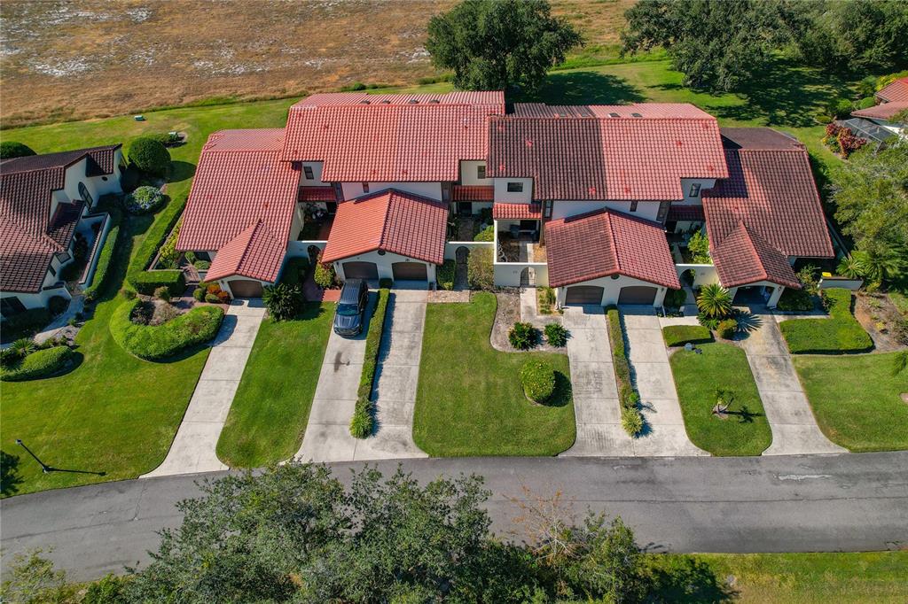 An aerial view of a multi-unit townhouse complex with red tile roofs and concrete driveways — 116 COVENTRY LN, HAINES CITY, FL