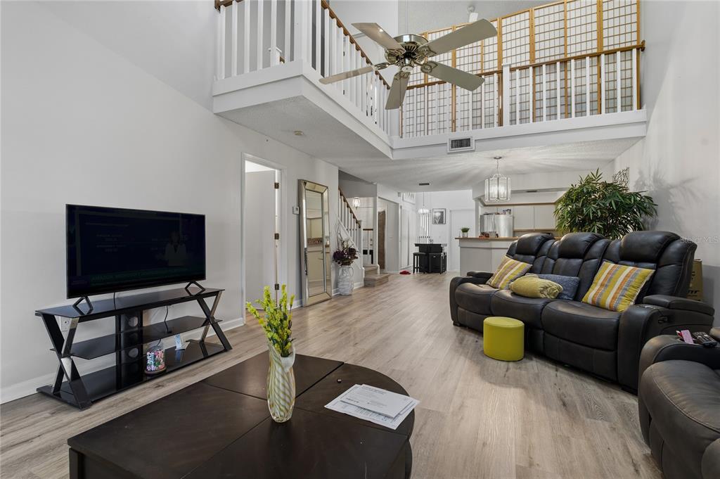 A living room with a high ceiling, a ceiling fan, and a black leather sofa — 116 COVENTRY LN, HAINES CITY, FL