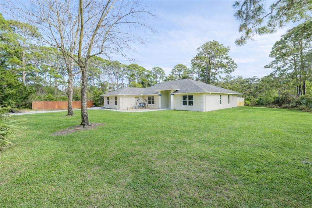 A single-story house with a light-colored exterior, a blue front door, and a grassy yard — 633 ART CENTER AVENUE, NEW SMYRNA BEACH, FL