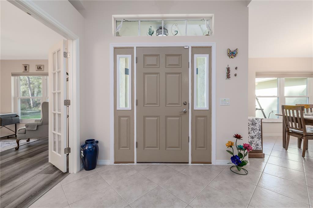 A foyer features a taupe front door with sidelights, a transom window, and tile flooring — 633 ART CENTER AVENUE, NEW SMYRNA BEACH, FL