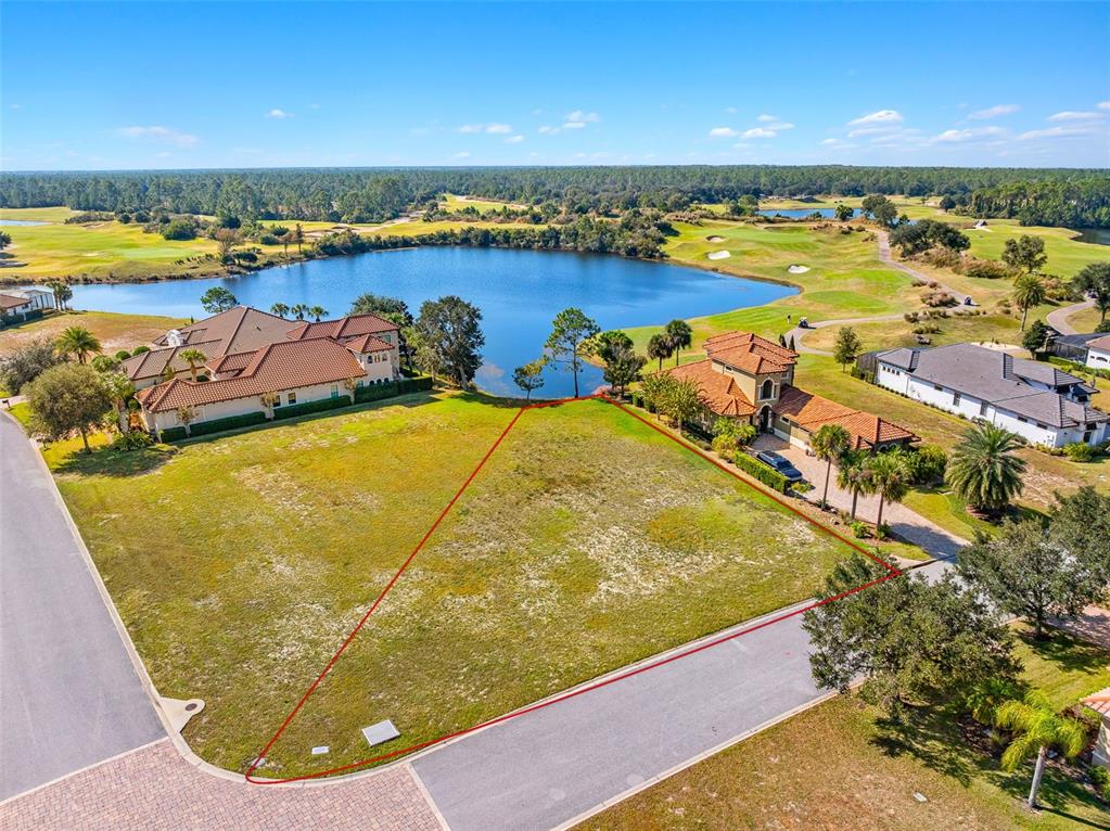 An aerial view shows a vacant, triangular residential lot situated between two houses and a lake — 201 ASPEN WAY, PALM COAST, FL