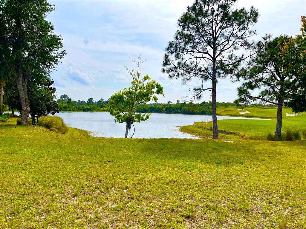A grassy lawn overlooks a pond and a golf course with several large trees — 201 ASPEN WAY, PALM COAST, FL