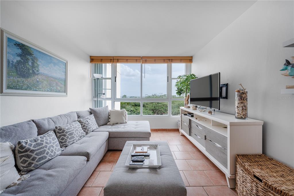 A living room features a gray sectional sofa, a television on a console, and large windows — SR-3301 km 2.8 interior VISTAMAR EL COMBATE CONDOMINIUM BEACH UNIT 410 C, CABO ROJO, PR
