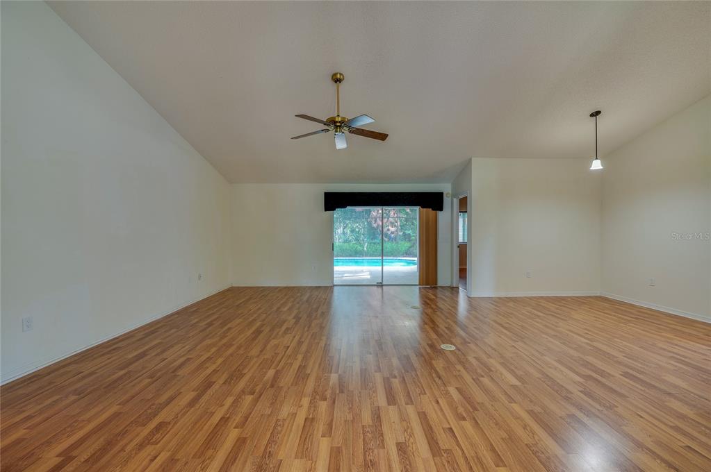 A spacious living room features wood-look flooring, a vaulted ceiling, and sliding glass doors — 203 LIVE OAK COURT, LAKE MARY, FL
