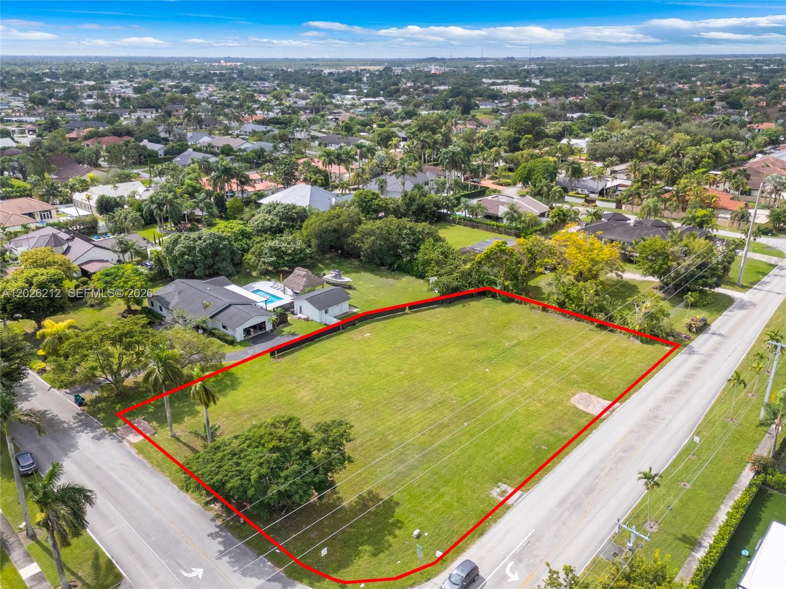 An aerial view shows a large, vacant rectangular lot outlined in red next to a house — 13600 SW 107th Ave, Miami FL 33176, MIAMI, FL