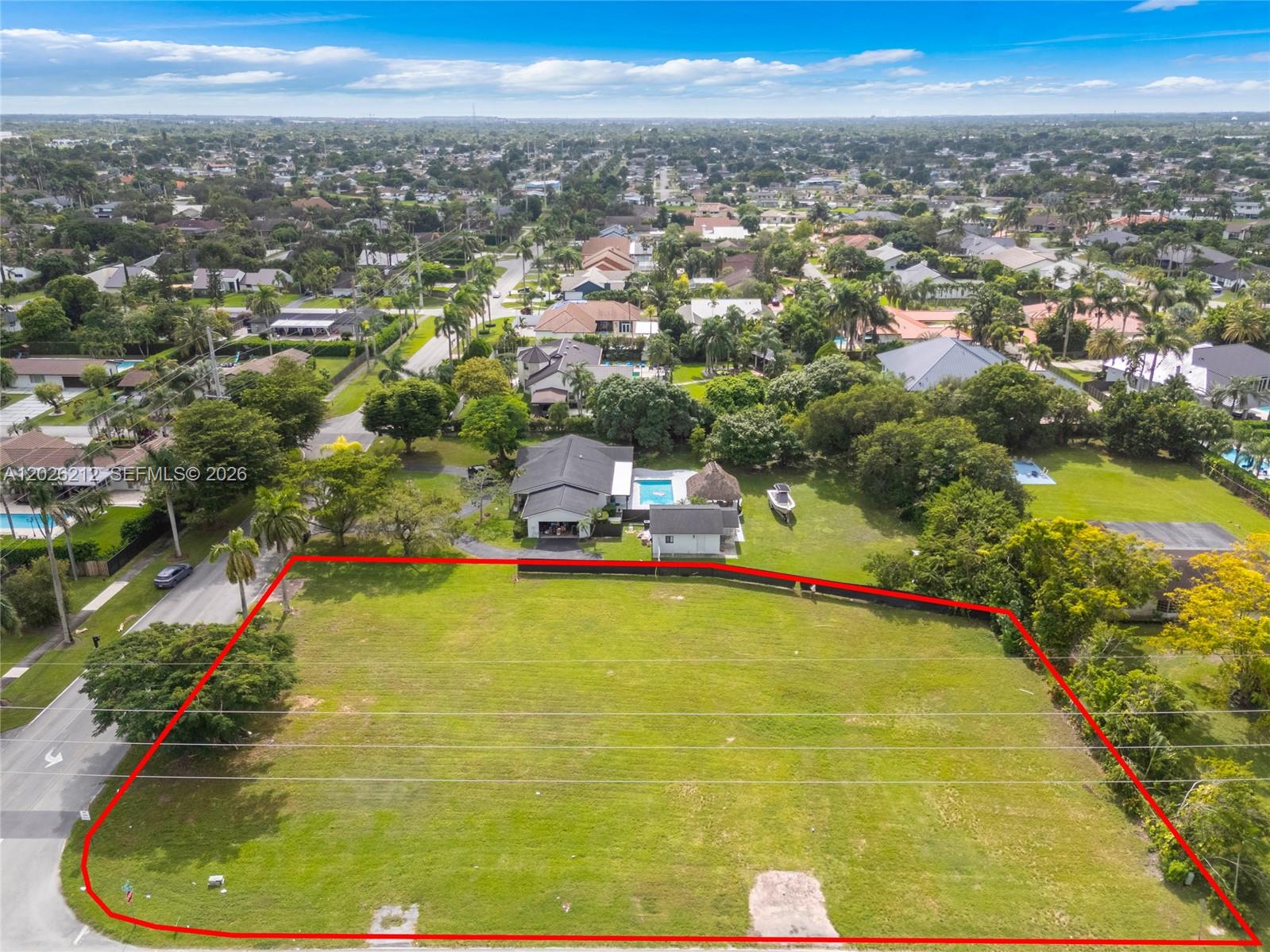 An aerial view shows a large, vacant grassy lot outlined in red next to a house — 13600 SW 107th Ave, Miami FL 33176, MIAMI, FL