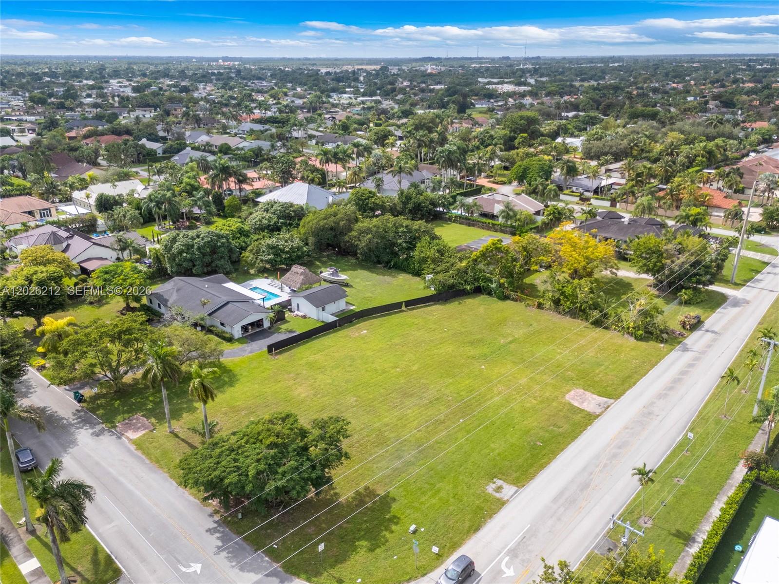An aerial view shows a house with a pool and a large, vacant grassy lot — 13600 SW 107th Ave, Miami FL 33176, MIAMI, FL