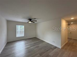 A kitchen features white cabinets, black appliances, a pendant light, and light wood-look flooring — 3717 N 56TH STREET UNIT B, TAMPA, FL
