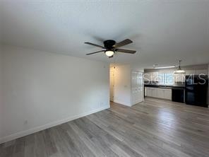 A kitchen with white cabinets, black appliances, dark countertops, and light wood-look flooring — 3717 N 56TH STREET UNIT B, TAMPA, FL