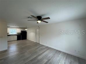 A kitchen features white cabinets, black appliances, and light wood-look flooring — 3717 N 56TH STREET UNIT B, TAMPA, FL
