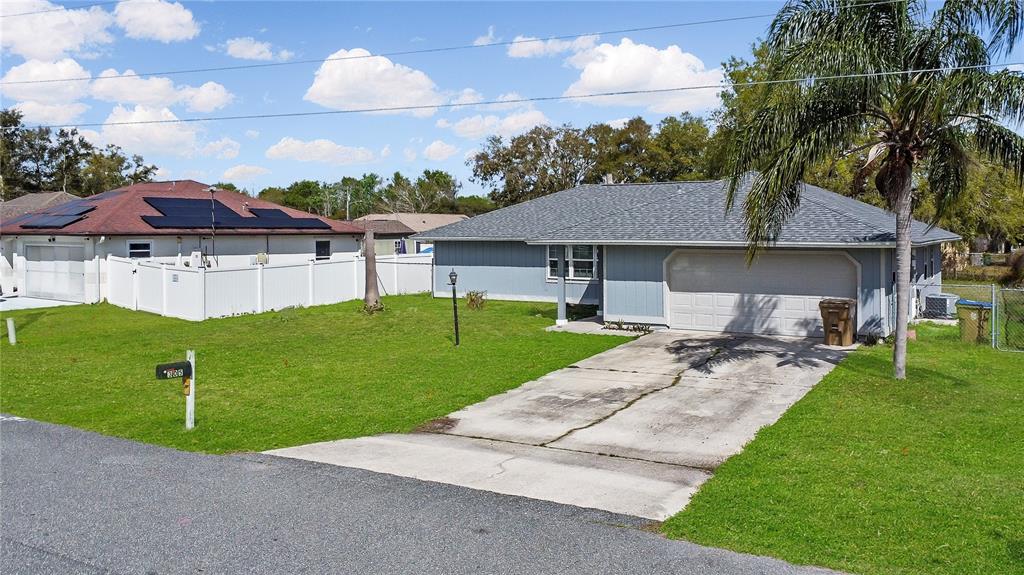 A single-story house with a gray exterior, a two-car garage, and a concrete driveway — 305 MEDINA COURT, KISSIMMEE, FL
