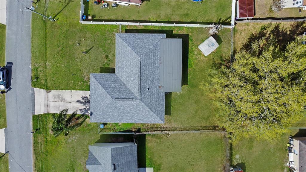 An aerial view shows a house with a gray shingled roof and a metal-roofed addition — 305 MEDINA COURT, KISSIMMEE, FL