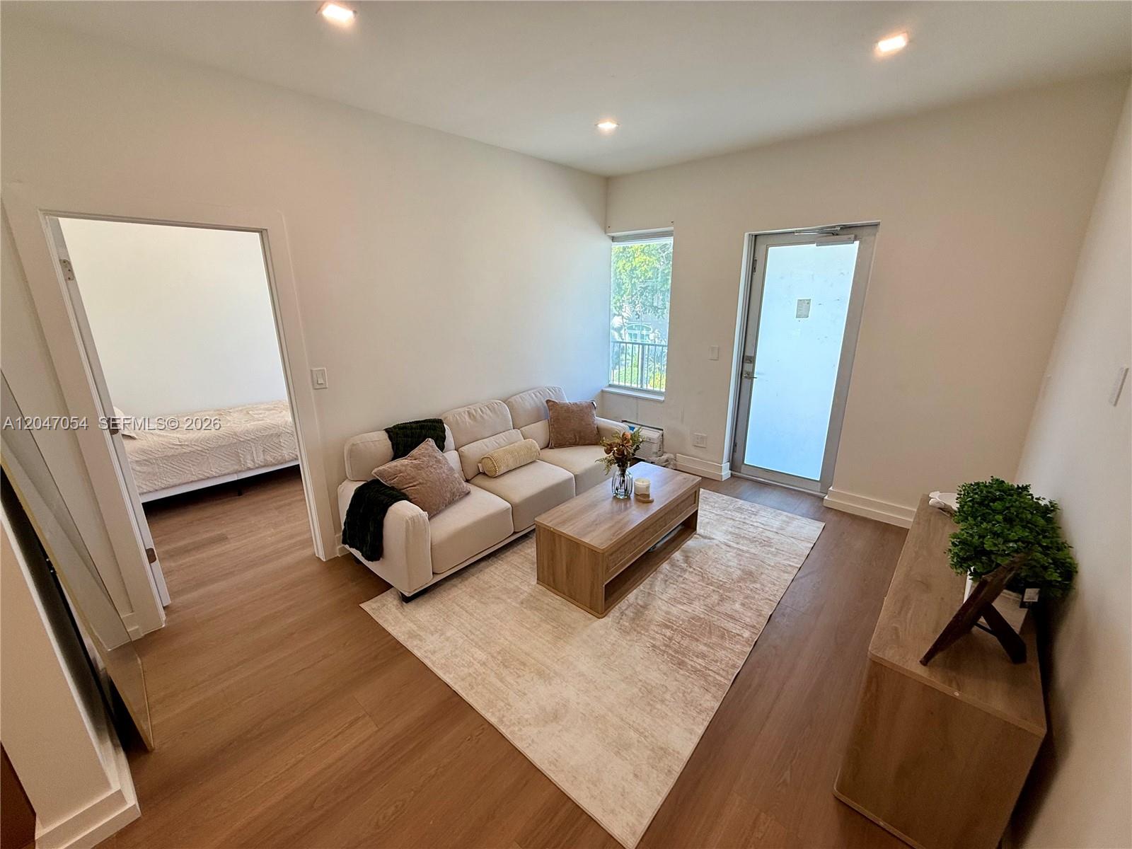 A living room features light wood flooring, a beige sofa, a coffee table, and an adjacent bedroom — 1535 West Ave # 4, Miami Beach FL 33139, MIAMI BEACH, FL