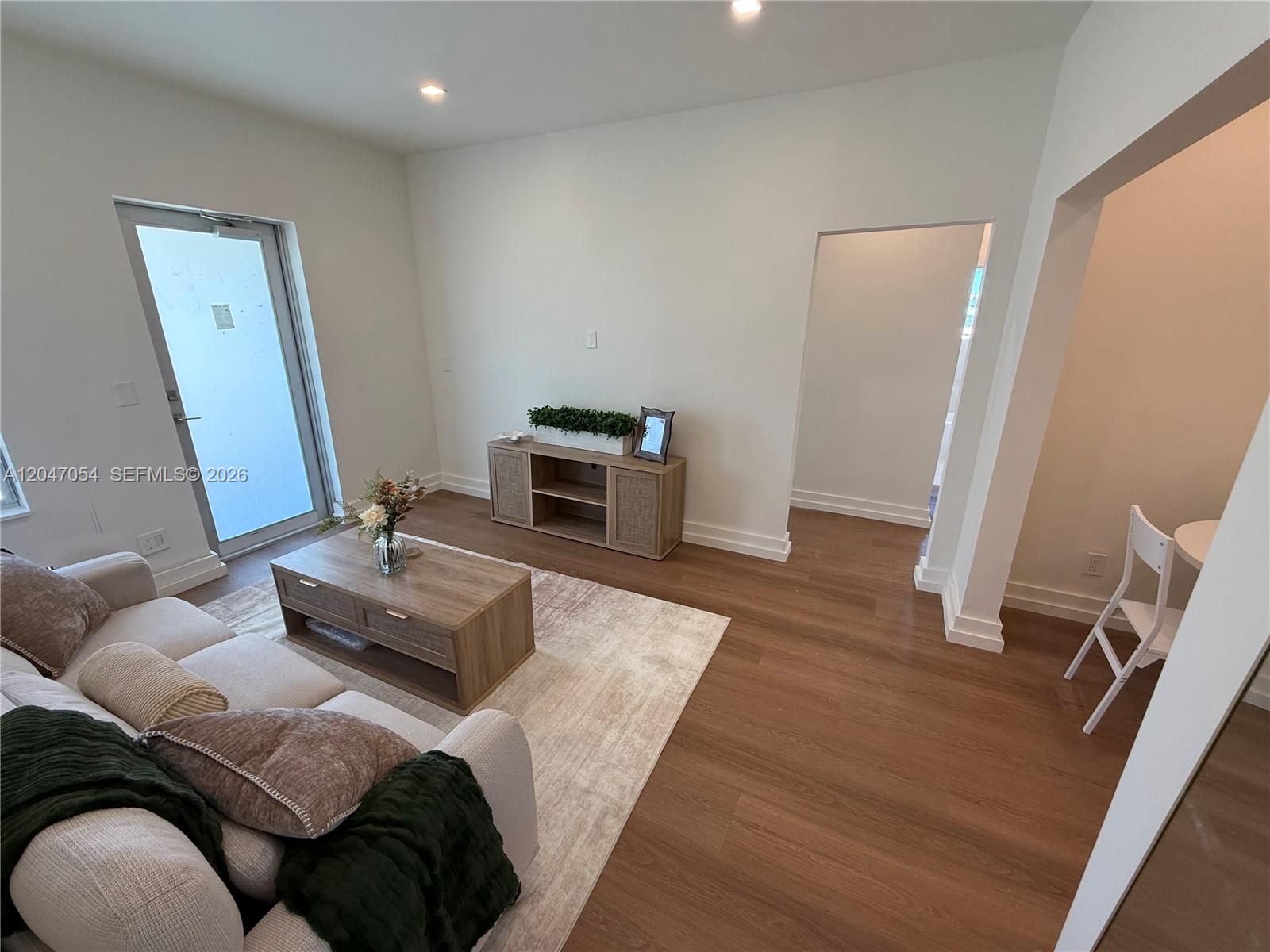 A living room features light wood flooring, a beige sofa, a coffee table, and a console — 1535 West Ave # 4, Miami Beach FL 33139, MIAMI BEACH, FL