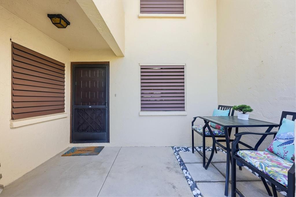 A patio features a metal table and chairs, a screen door, and brown window shutters — 5216 LAKE VILLAGE DRIVE UNIT 71, SARASOTA, FL