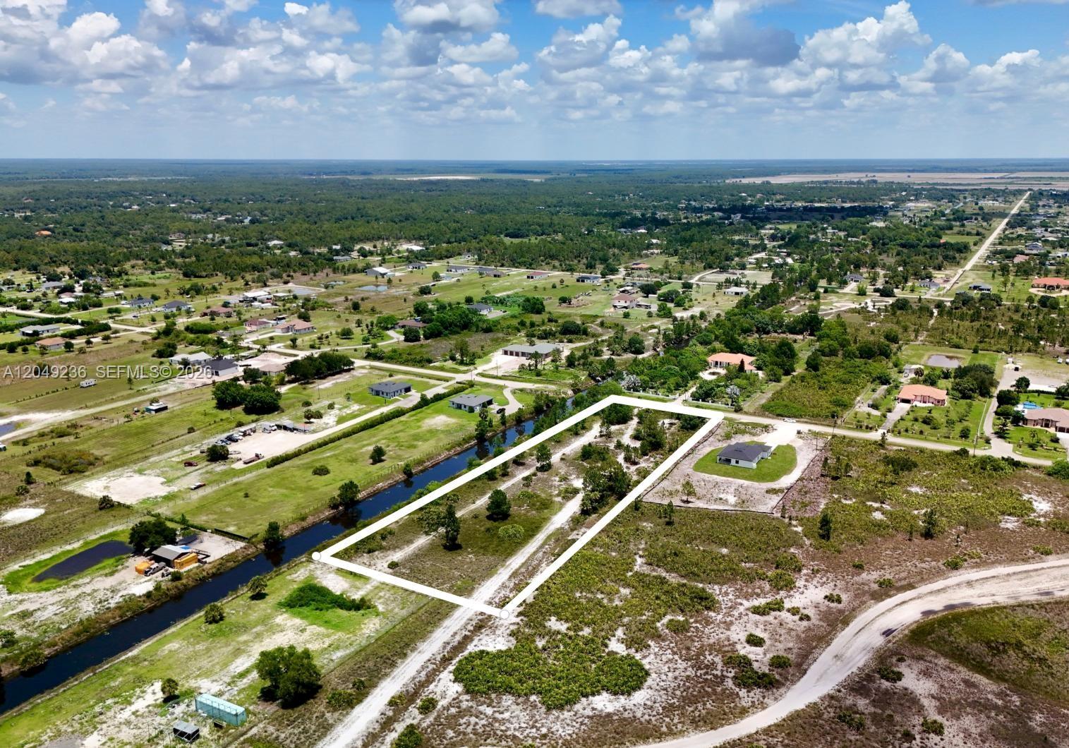 An aerial view shows a rectangular vacant lot bordered by a canal and dirt roads — 0 60th Ave NE, Naples FL 34120, NAPLES, FL