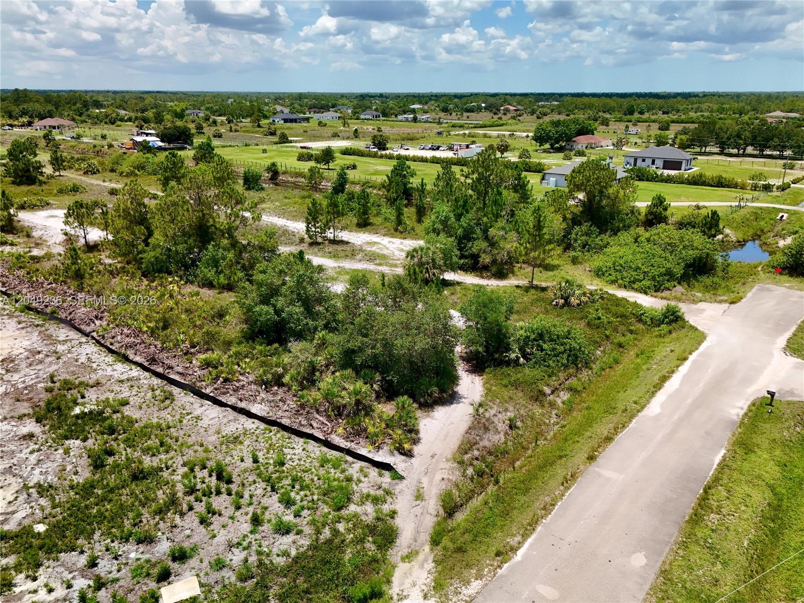 An aerial view shows a vacant, partially wooded lot next to a paved road — 0 60th Ave NE, Naples FL 34120, NAPLES, FL