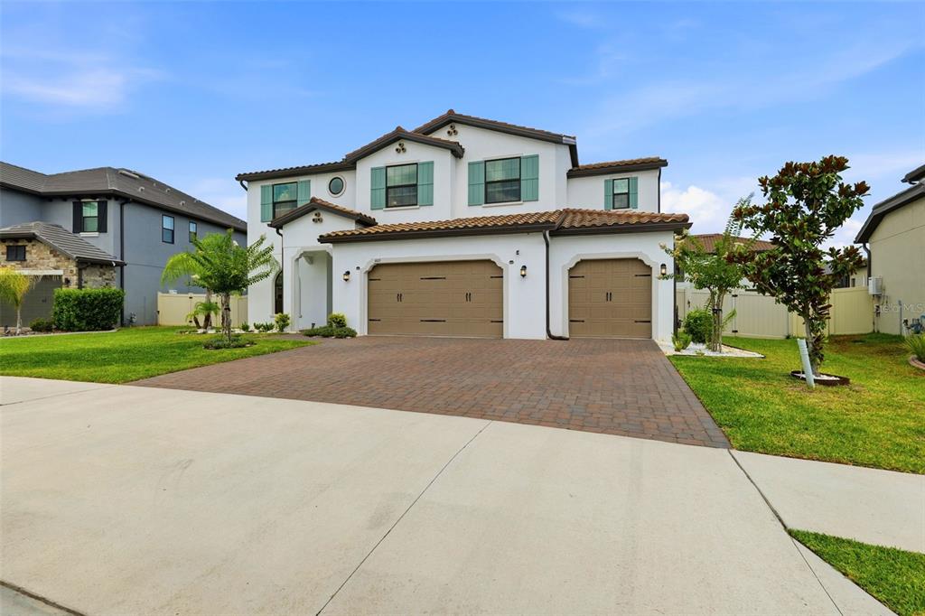 A two-story house with a three-car garage and a paved driveway under a blue sky — 6015 MARSH TRAIL DRIVE, ODESSA, FL