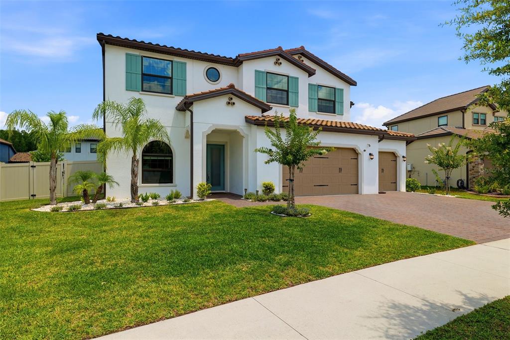 A two-story suburban house with a white stucco exterior, teal shutters, and a paved driveway — 6015 MARSH TRAIL DRIVE, ODESSA, FL
