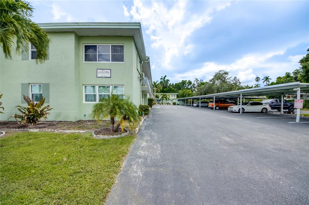 A light green two-story apartment building with a covered parking area and palm trees — 2544 1ST STREET UNIT 107, FORT MYERS, FL