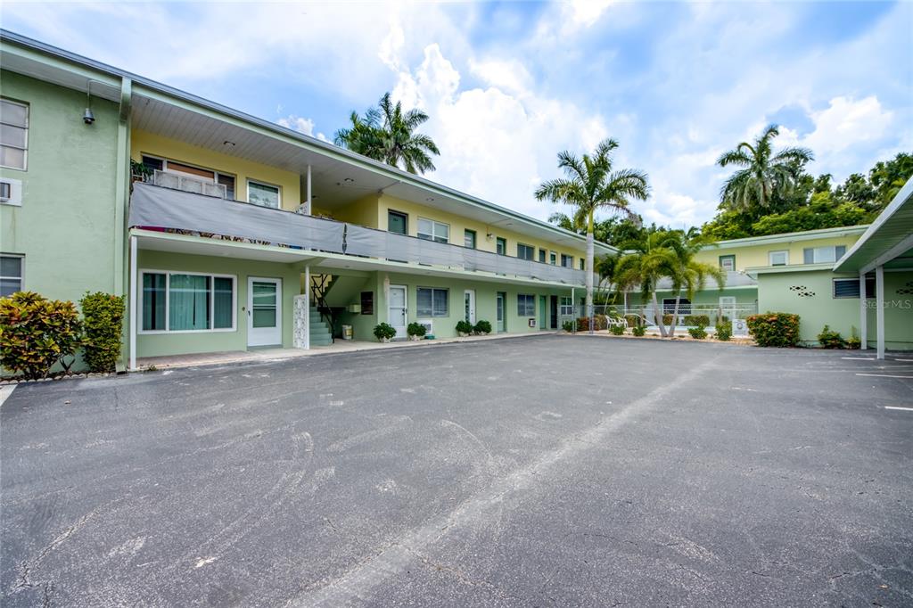 A two-story light green apartment building with a large asphalt parking lot in front — 2544 1ST STREET UNIT 107, FORT MYERS, FL